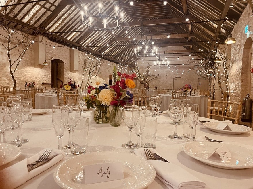 A wedding reception table laid with flowers and place settings